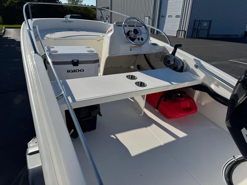 Slide: The Image of 2025 Boston Whaler 130 Super Sport interior with steering wheel, Igloo cooler, and storage compartments. - 5