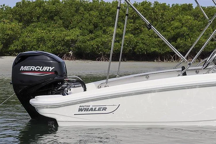 Slide: The Image of 2025 Boston Whaler 130 Super Sport boat with Mercury engine near lush shoreline. - 8