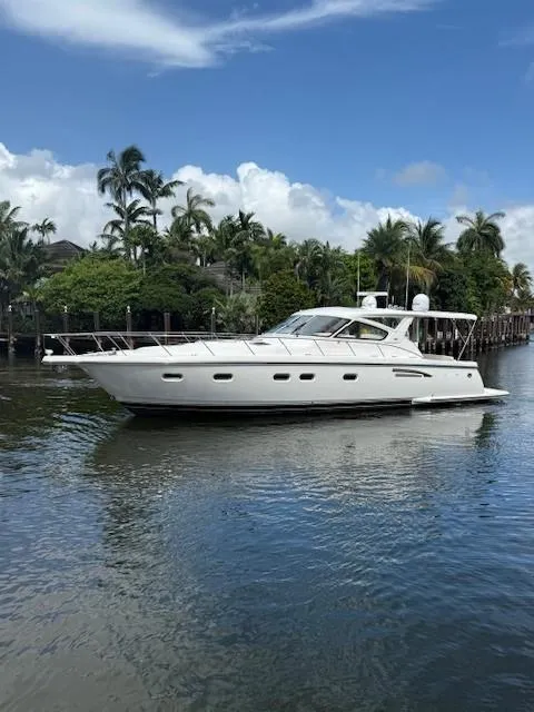 Slide: The Image of 2000 Tiara Yachts 5200 Express cruising on a serene waterway with lush greenery. - 1