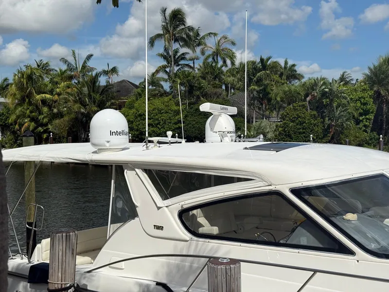 Slide: The Image of 2000 Tiara Yachts 5200 Express docked, featuring Garmin and Intellian equipment, surrounded by lush greenery. - 21
