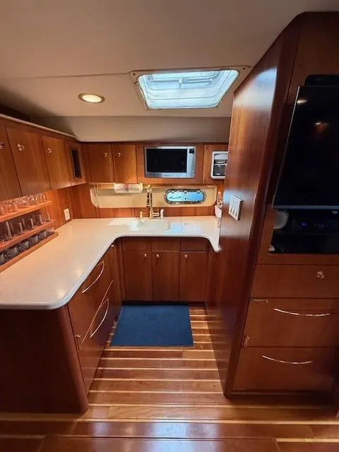 Slide: The Image of Interior of 2000 Tiara Yachts 5200 Express, featuring a modern kitchen with wood cabinetry. - 34
