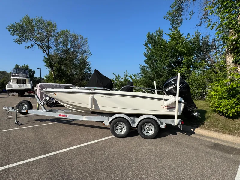 Slide: The Image of 2011 Boston Whaler 180 Dauntless boat on trailer, parked outdoors with trees in background. - 0