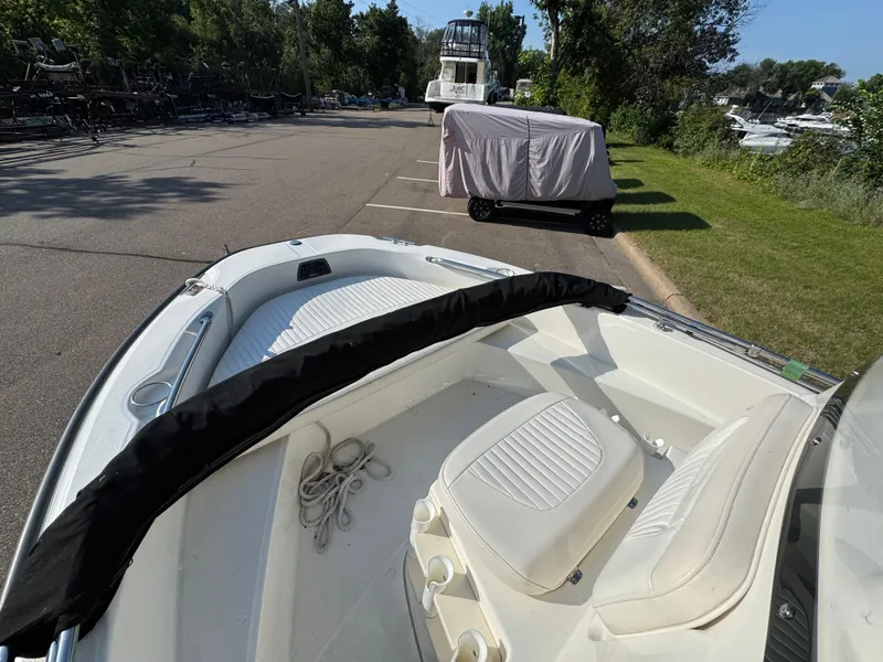 Slide: The Image of 2011 Boston Whaler 180 Dauntless boat interior with seating and rope, parked near marina. - 10