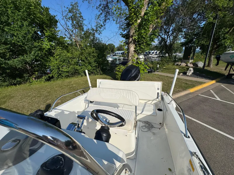 Slide: The Image of 2011 Boston Whaler 180 Dauntless boat interior with steering wheel, parked near trees and marina. - 13
