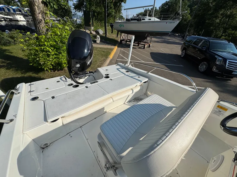 Slide: The Image of 2011 Boston Whaler 180 Dauntless boat interior with seating and motor, parked near trees. - 15