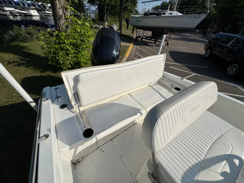 Slide: The Image of 2011 Boston Whaler 180 Dauntless boat interior with white seating and motor, docked near other boats. - 17