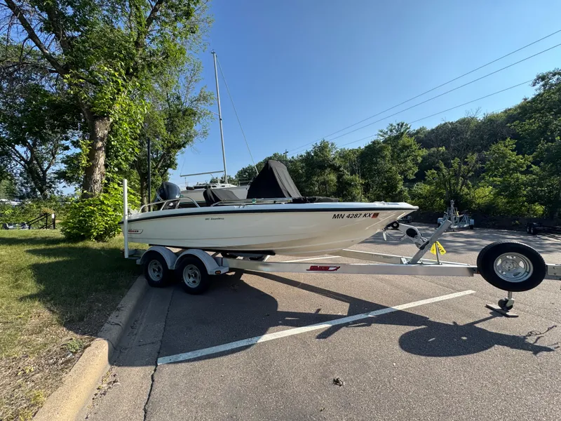 Slide: The Image of 2011 Boston Whaler 180 Dauntless boat on trailer, parked in a sunny, wooded area. - 2