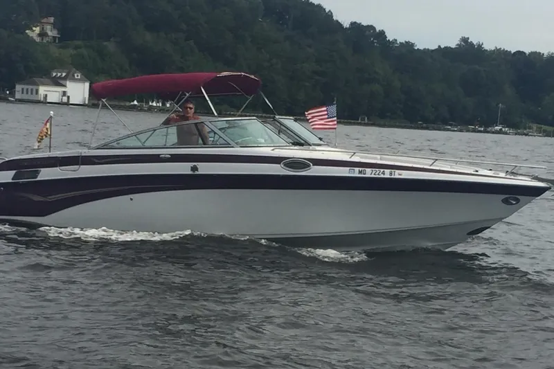 Slide: The Image of 2004 Crownline 288 BR boat cruising on a lake with American flag. - 12