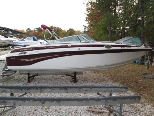 Slide: The Image of 2004 Crownline 288 BR boat on trailer, parked outdoors with trees in background. - 7