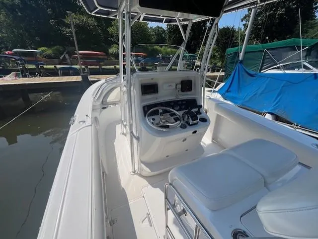 Slide: The Image of 2004 Boston Whaler 270 Outrage boat interior with helm and seating, docked near water. - 13
