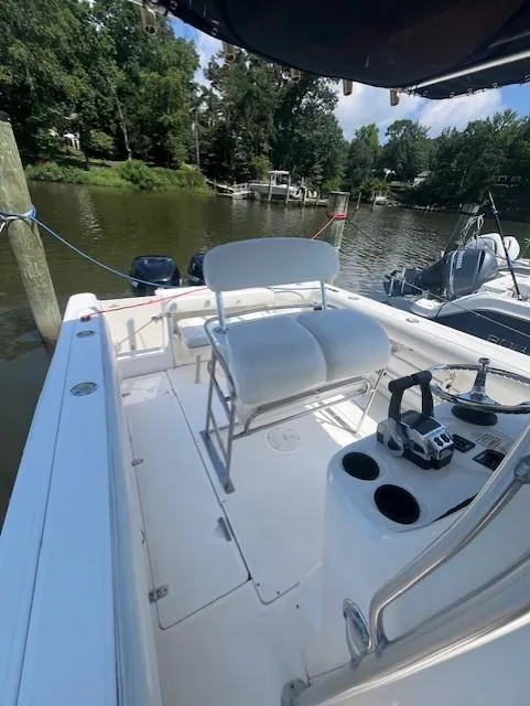 Slide: The Image of 2004 Boston Whaler 270 Outrage boat interior with seating and controls, docked by a serene river. - 15