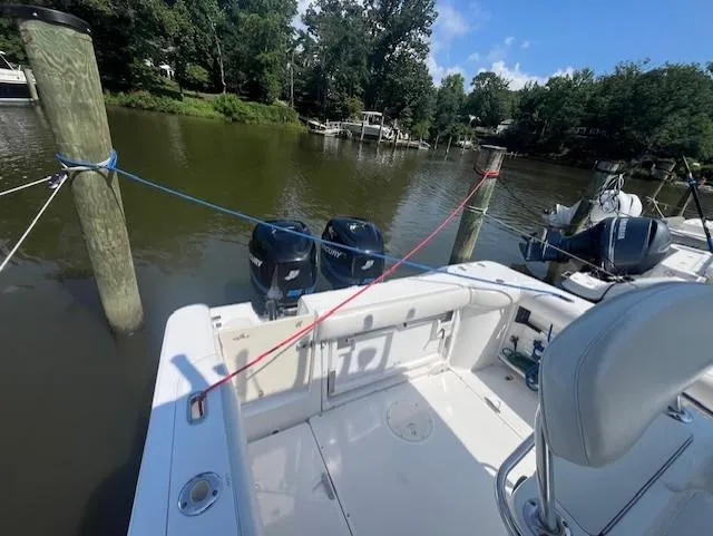 Slide: The Image of 2004 Boston Whaler 270 Outrage docked, featuring dual outboard motors, surrounded by serene water and trees. - 17