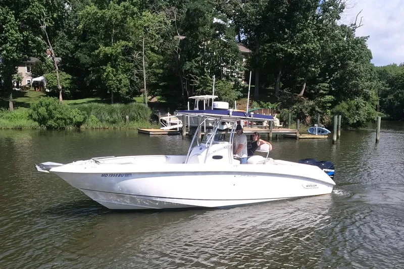 Slide: The Image of 2004 Boston Whaler 270 Outrage boat cruising on a calm river near a wooded shoreline. - 3