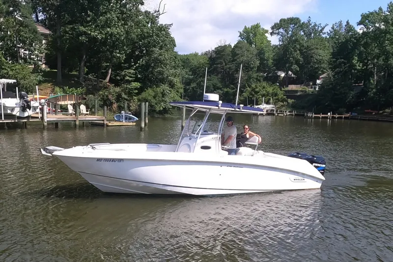 Slide: The Image of 2004 Boston Whaler 270 Outrage boat on a calm river with lush greenery. - 4