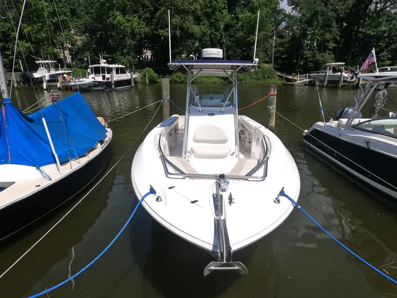 Slide: The Image of 2004 Boston Whaler 270 Outrage boat docked between other vessels in a serene marina. - 6