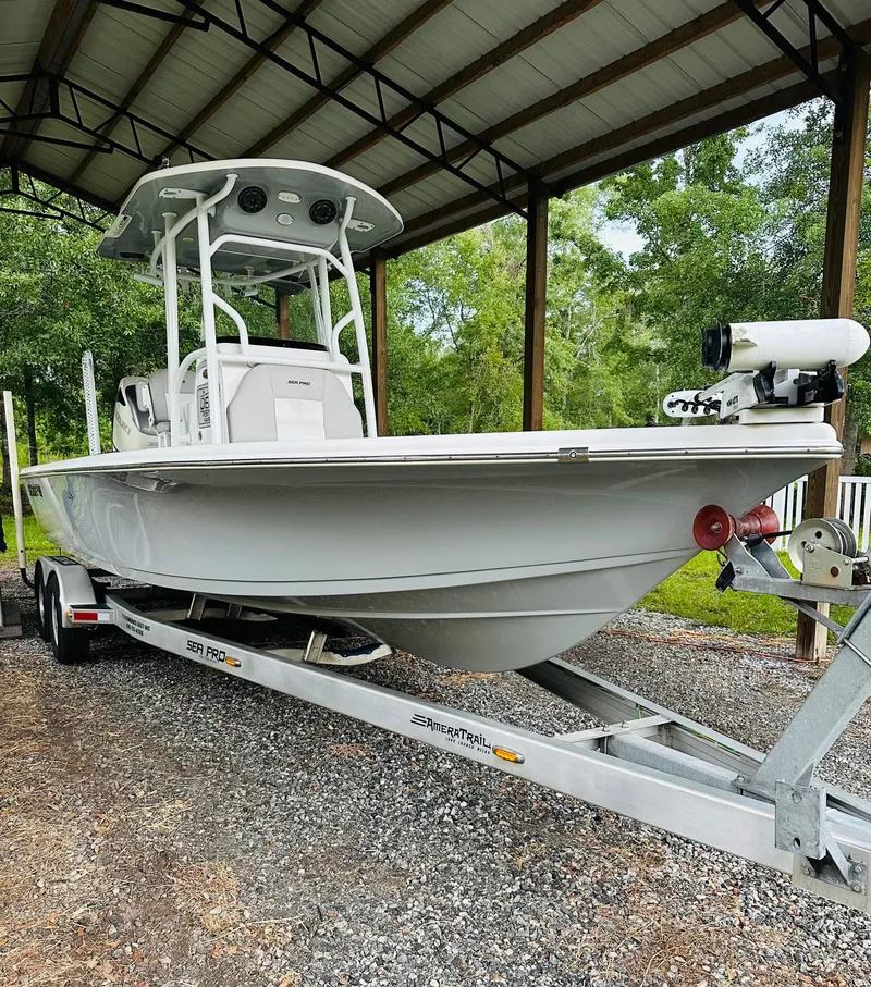 Slide: The Image of 2019 Sea Pro 248 Bay boat on trailer under shelter, surrounded by trees. - 2
