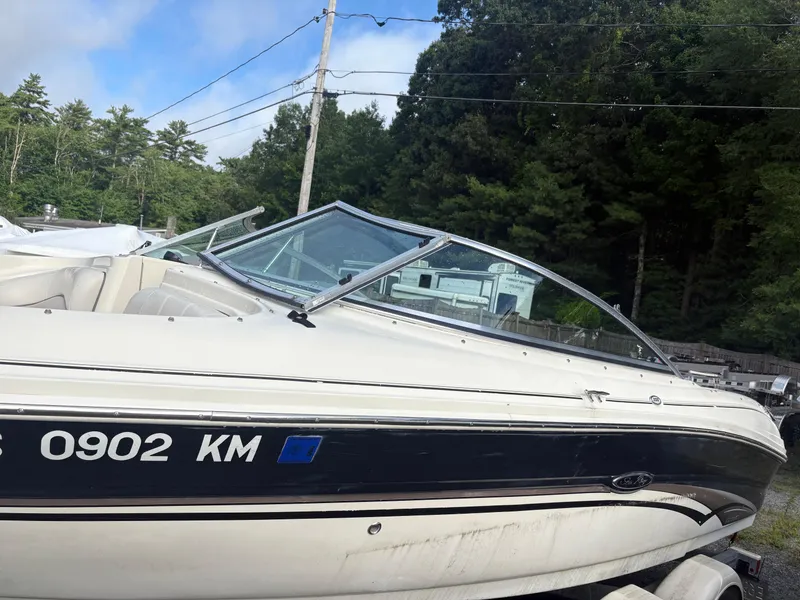 Slide: The Image of 2003 Sea Ray 200 Bow Rider boat on trailer, surrounded by trees and power lines. - 2