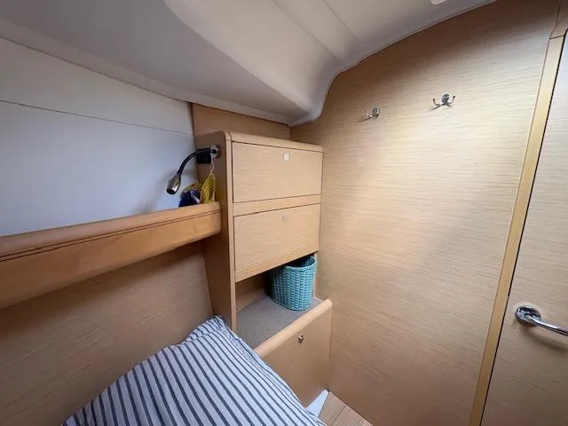 Slide: The Image of Cozy cabin interior of 2018 Jeanneau Sun Odyssey 389 with striped bedding and wooden storage. - 18