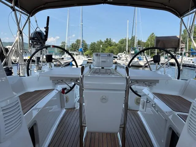 Slide: The Image of 2018 Jeanneau Sun Odyssey 389 cockpit with dual steering wheels, docked at a marina. - 3