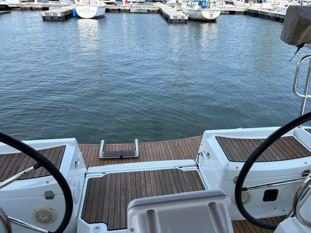 Slide: The Image of 2018 Jeanneau Sun Odyssey 389 sailboat docked at marina, featuring dual steering wheels. - 4