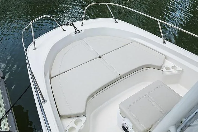 Slide: The Image of 2025 Boston Whaler 190 Montauk boat with cushioned seating, docked on calm water. - 12