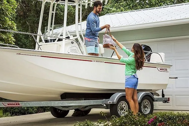 Slide: The Image of Couple loading items onto a 2025 Boston Whaler 190 Montauk boat on a trailer. - 13