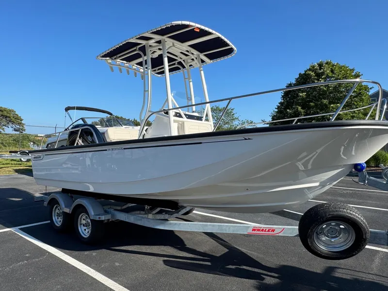 Slide: The Image of 2025 Boston Whaler 190 Montauk boat on trailer, parked outdoors under clear blue sky. - 3