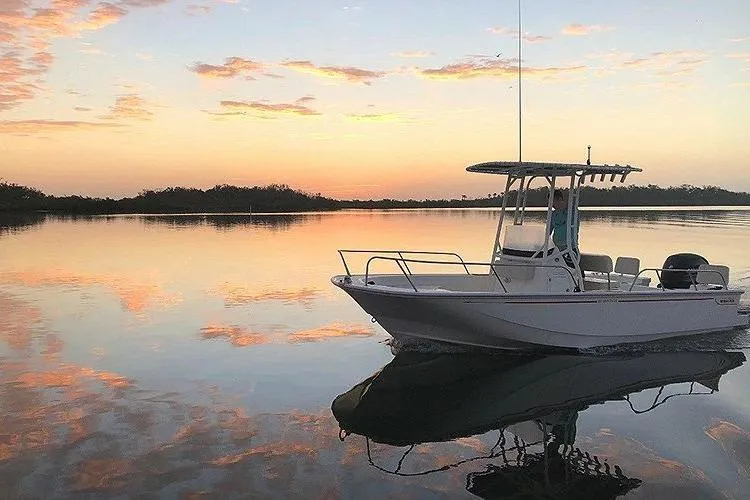 Slide: The Image of 2025 Boston Whaler 190 Montauk boat on calm water at sunset. - 8