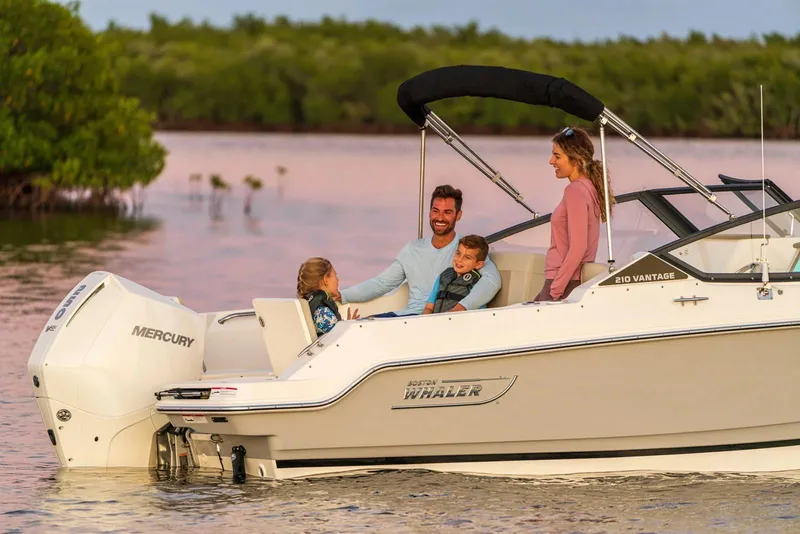 Slide: The Image of Family enjoying a 2025 Boston Whaler 210 Vantage boat on serene waters. - 10