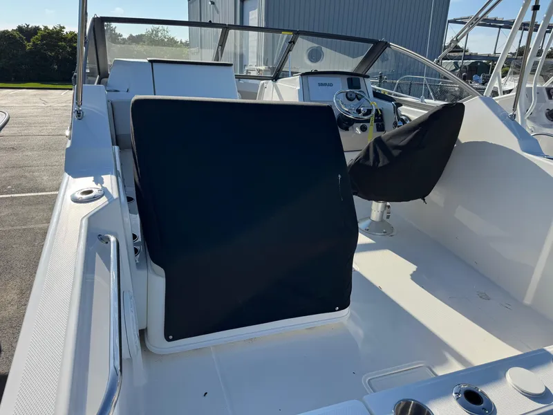 Slide: The Image of 2025 Boston Whaler 210 Vantage boat interior with covered seating and steering console. - 6