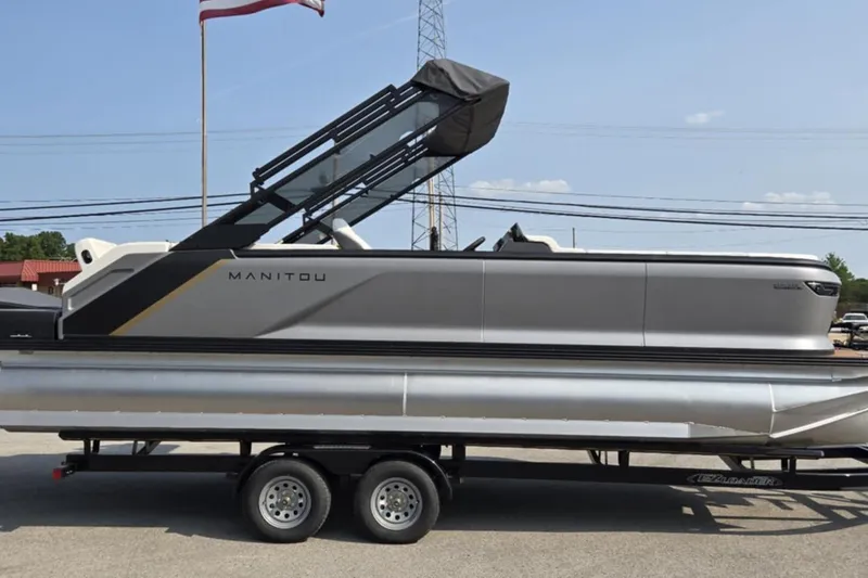 The Image of 2025 Manitou Explore pontoon boat on trailer, side view, outdoors. - 0