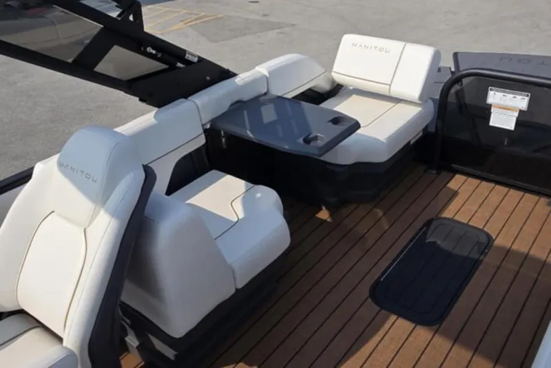 Slide: The Image of 2025 Manitou Explore boat interior with white seating and wooden deck. - 10