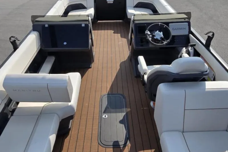 Slide: The Image of 2025 Manitou Explore boat interior with modern seating and Garmin navigation system. - 11