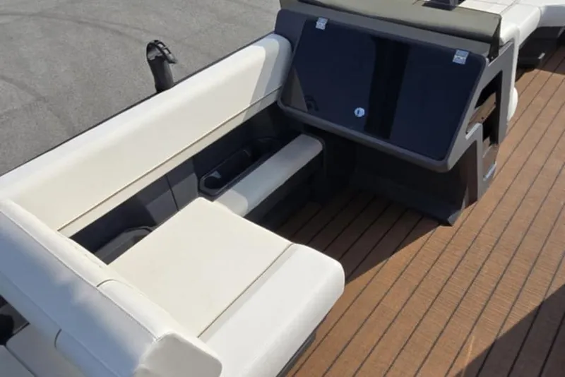 Slide: The Image of 2025 Manitou Explore boat interior with beige seating and wooden deck. - 12