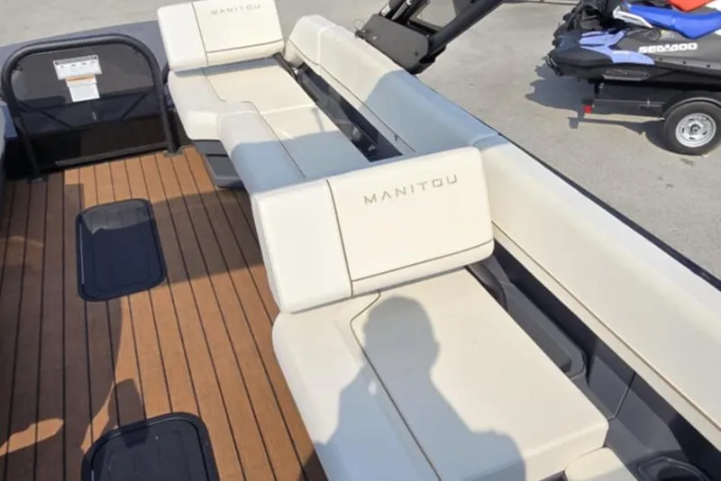 Slide: The Image of 2025 Manitou Explore boat interior with beige seating and wooden deck. - 14