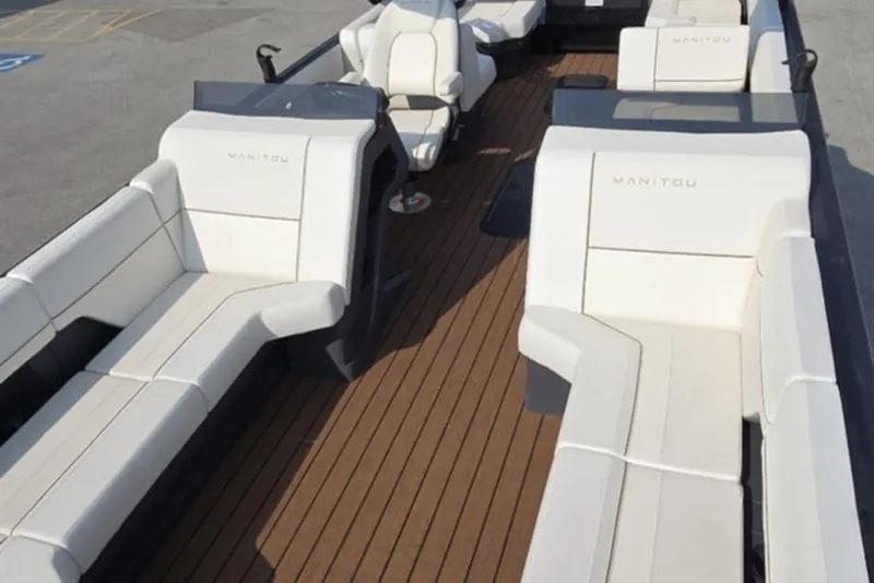 Slide: The Image of 2025 Manitou Explore boat interior with white seating and wooden deck. - 17
