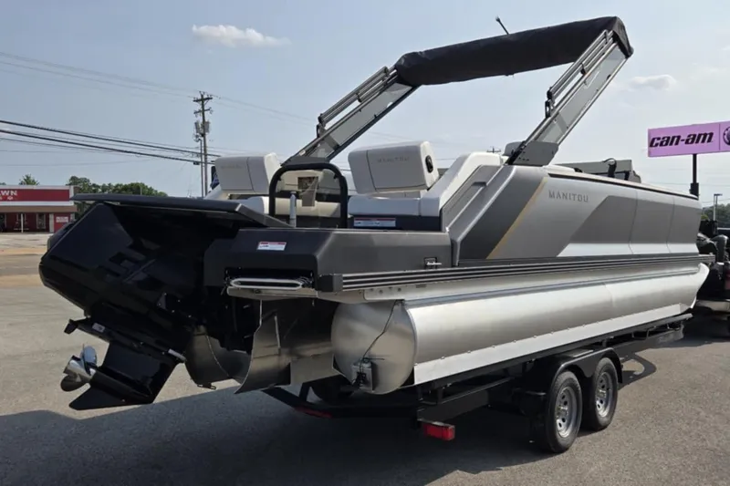 Slide: The Image of 2025 Manitou Explore pontoon boat on trailer, parked outdoors. - 6