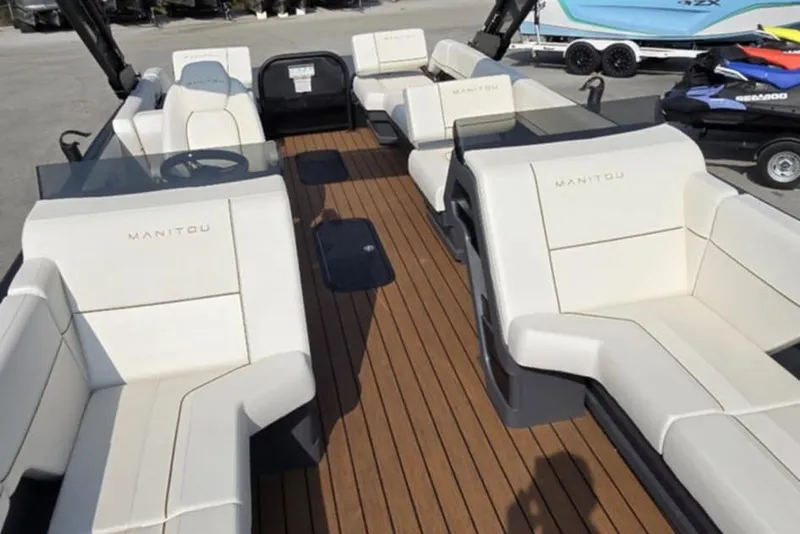 Slide: The Image of 2025 Manitou Explore boat interior with white seating and wooden deck. - 8