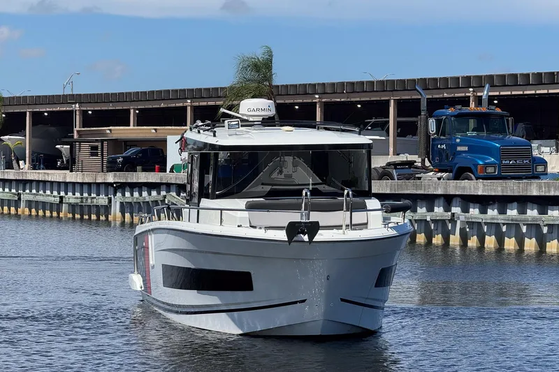 Slide: The Image of 2018 Jeanneau NC 895 boat docked near industrial area with truck in background. - 10