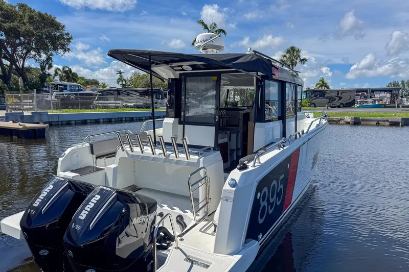 Slide: The Image of 2018 Jeanneau NC 895 boat docked, featuring twin Mercury V6 engines, under a clear blue sky. - 12