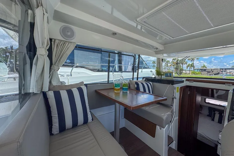 Slide: The Image of Interior of 2018 Jeanneau NC 895 boat with seating, table, and striped cushions. - 15