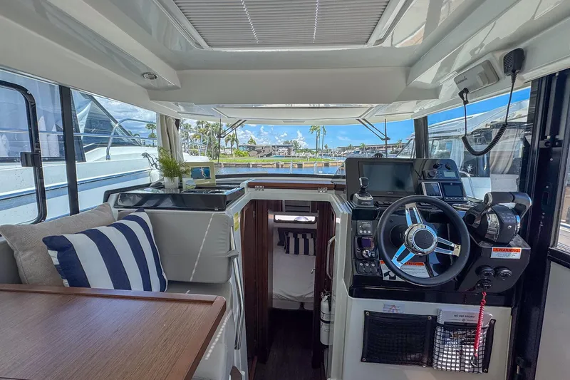 Slide: The Image of Interior of 2018 Jeanneau NC 895 boat with helm, seating, and scenic marina view. - 16