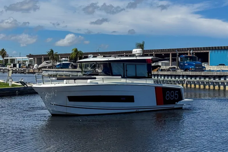Slide: The Image of 2018 Jeanneau NC 895 boat on a calm waterway, with marina and blue sky background. - 2