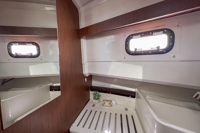 Slide: The Image of 2018 Jeanneau NC 895 cabin interior with window, wooden accents, and storage space. - 23