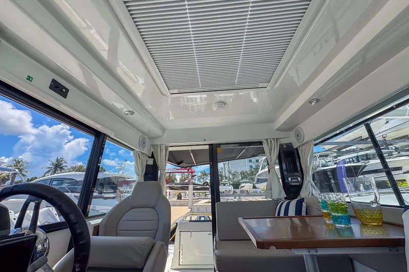 Slide: The Image of Interior of 2018 Jeanneau NC 895 boat with seating, table, and glassware under a sunny sky. - 27