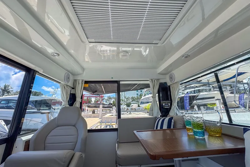 Slide: The Image of Interior of 2018 Jeanneau NC 895 boat with seating and table, featuring colorful drinks. - 28