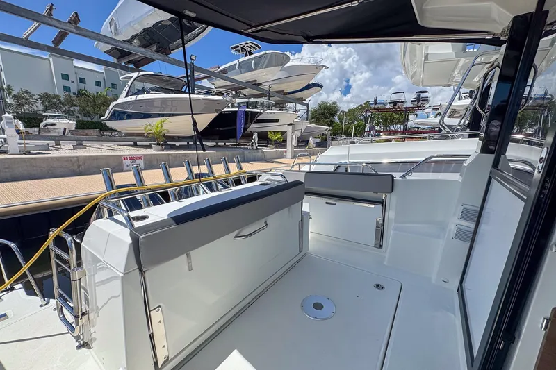 Slide: The Image of 2018 Jeanneau NC 895 boat deck with seating, docked at marina under clear sky. - 30