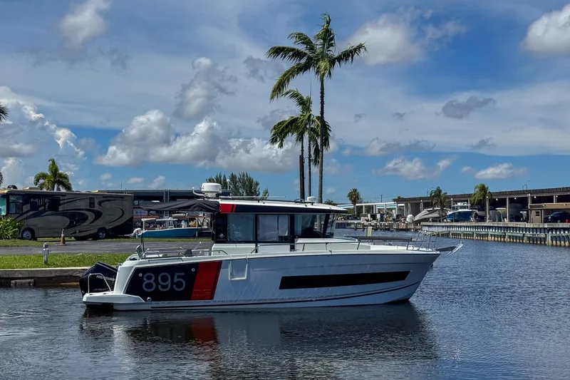 Slide: The Image of 2018 Jeanneau NC 895 boat docked on a sunny day with palm trees in the background. - 4