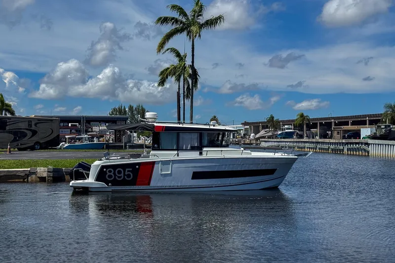 Slide: The Image of 2018 Jeanneau NC 895 boat docked on a sunny day with palm trees in the background. - 6
