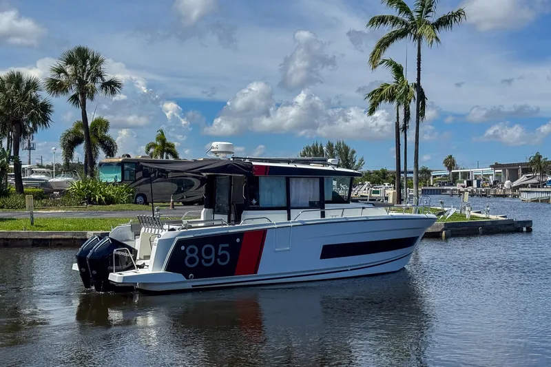 Slide: The Image of 2018 Jeanneau NC 895 boat docked by palm trees under a blue sky. - 8